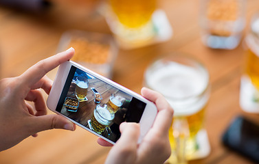 Image showing close up of hands with smartphone picturing beer