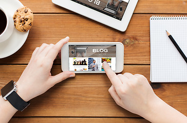 Image showing close up of woman with smartphone on wooden table