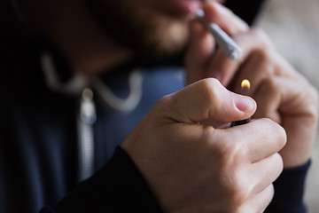 Image showing close up of addict lighting up marijuana joint