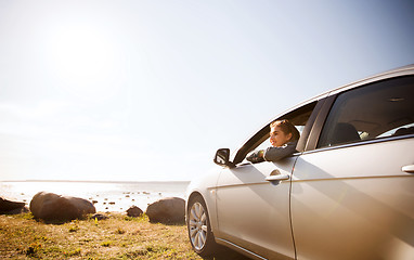 Image showing happy teenage girl or young woman in car