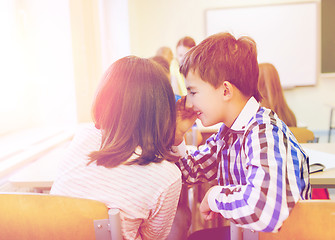 Image showing smiling schoolgirl whispering to classmate ear