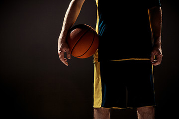 Image showing Silhouette view of a basketball player holding basket ball on black background