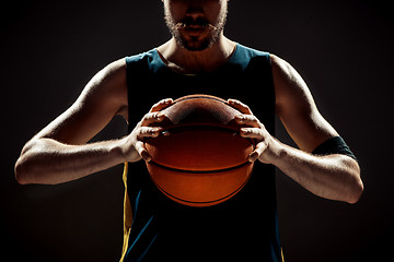 Image showing Silhouette view of a basketball player holding basket ball on black background