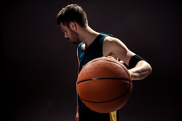 Image showing Silhouette view of a basketball player holding basket ball on black background