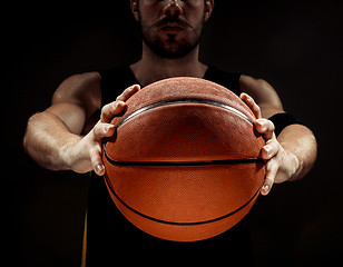 Image showing Silhouette view of a basketball player holding basket ball on black background