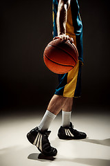 Image showing Silhouette view of a basketball player holding basket ball on black background