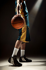 Image showing Silhouette view of a basketball player holding basket ball on black background