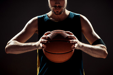 Image showing Silhouette view of a basketball player holding basket ball on black background