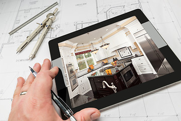 Image showing Hand of Architect on Computer Tablet Showing Kitchen Photo Over 