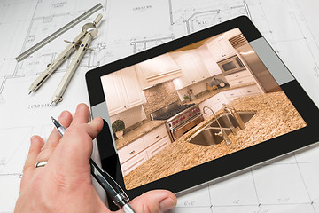 Image showing Hand of Architect on Computer Tablet Showing Kitchen Photo Over 