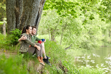 Image showing happy couple with cups drinking tea in nature