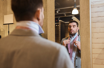 Image showing man tying tie on at mirror in clothing store