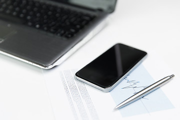 Image showing close up of smartphone, laptop and pen on table