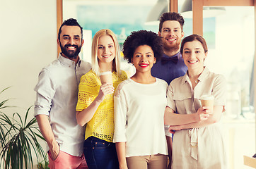 Image showing happy smiling creative team with coffee in office