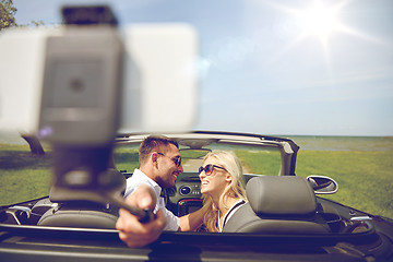 Image showing happy couple in car taking selfie with smartphone