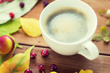 Image showing close up of coffee cup on table with autumn leaves