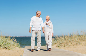 Image showing happy senior couple holding hands on summer beach