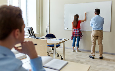 Image showing teacher and student writing on board at school