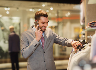 Image showing happy man calling on smartphone at clothing store