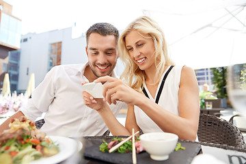 Image showing happy couple with smatphone at restaurant terrace