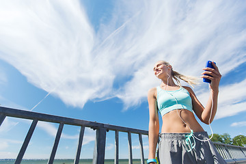 Image showing happy woman with smartphone and earphones outdoors