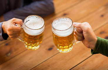 Image showing close up of hands with beer mugs at bar or pub