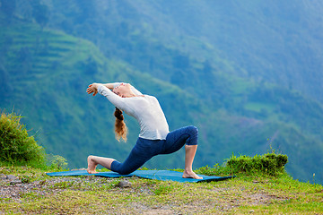 Image showing Sporty fit woman practices yoga asana Anjaneyasana in mountains