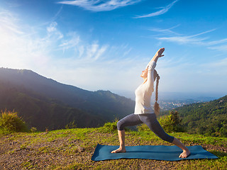 Image showing Woman doing yoga asana Virabhadrasana 1 - Warrior pose outdoors