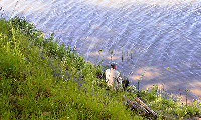 Image showing  A fisherman with a fishing rod on the river bank