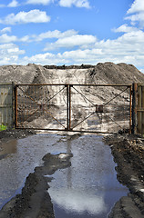 Image showing Dirt road, a pool and a lot of stored in the open air ground for a closed fence