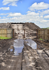 Image showing Dirt road, a pool and a lot of stored in the open air ground for a closed fence