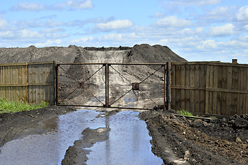 Image showing Dirt road, a pool and a lot of stored in the open air ground for a closed fence