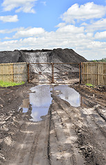 Image showing Dirt road, a pool and a lot of stored in the open air ground for a closed fence