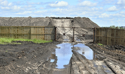 Image showing Dirt road, a pool and a lot of stored in the open air ground for a closed fence