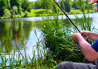 Image showing  Close up of guy sitting on bridge and fishing