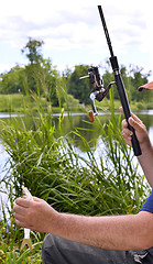 Image showing  Close up of guy sitting on bridge and fishing