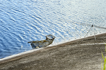 Image showing Fish Tank and fishing rod on the shore of the lake on a backgrou