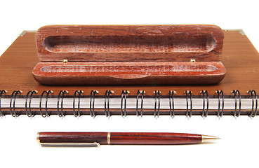 Image showing pen in an opened wooden case on notebook