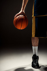 Image showing Silhouette view of a basketball player holding basket ball on black background