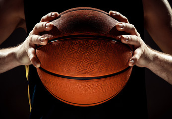 Image showing Silhouette view of a basketball player holding basket ball on black background