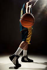 Image showing Silhouette view of a basketball player holding basket ball on black background