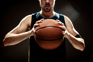 Image showing Silhouette view of a basketball player holding basket ball on black background