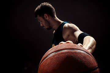 Image showing Silhouette view of a basketball player holding basket ball on black background