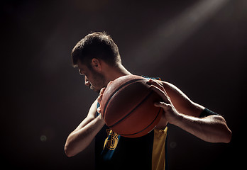 Image showing Silhouette view of a basketball player holding basket ball on black background