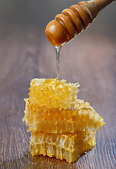 Image showing Honey dripping from a wooden drizzler over honeycomb