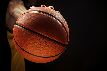 Image showing Silhouette view of a basketball player holding basket ball on black background