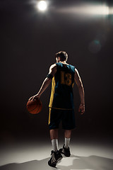 Image showing Silhouette view of a basketball player holding basket ball on black background