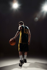 Image showing Silhouette view of a basketball player holding basket ball on black background