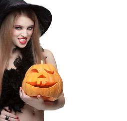 Image showing Woman in witch costume opens carved Halloween pumpkin