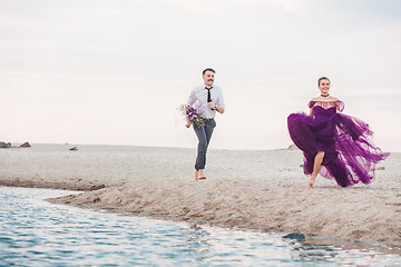 Image showing Young romantic couple running on the beach of sea